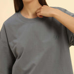 Woman wearing an oversized French terry t-shirt for women in dark grey with an embroidered logo.