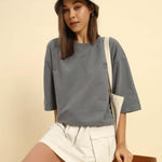 woman wearing dark grey oversized French terry t-shirt for women with a bucket hat and beige skirt