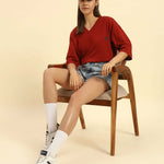 Model seated wearing the Aeternum Oversized V-Neck T-Shirt in Red, demonstrating the versatile loungewear style.