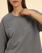 Woman wearing an oversized French terry t-shirt for women in dark grey with an embroidered logo.