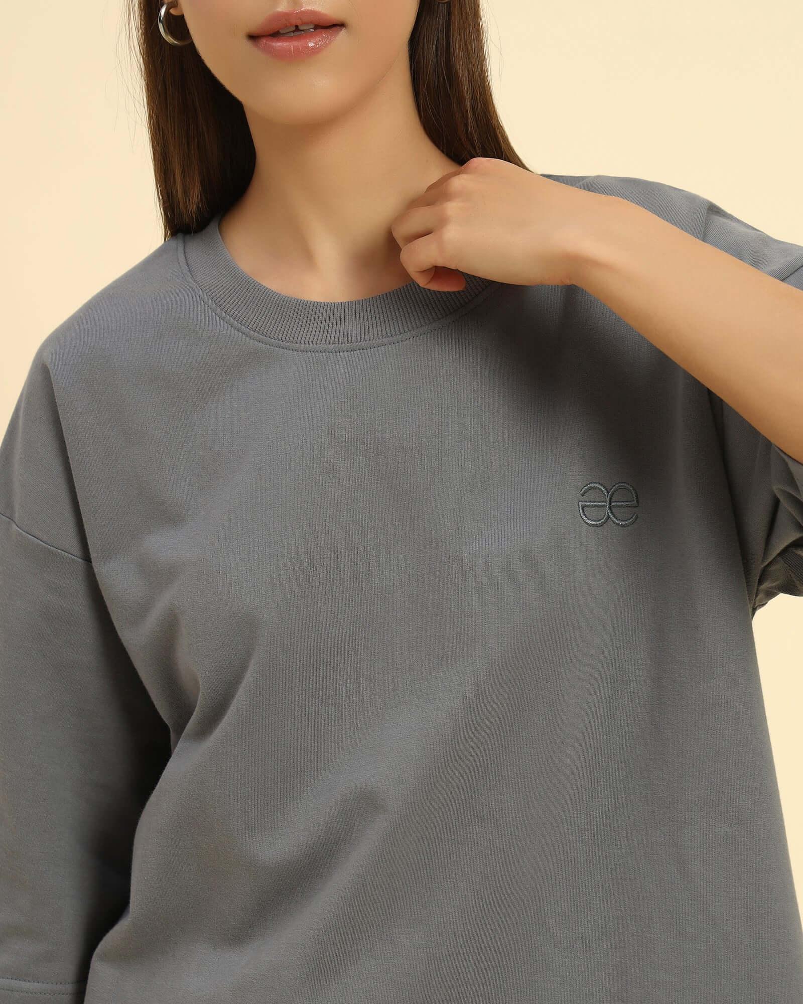 Woman wearing an oversized French terry t-shirt for women in dark grey with an embroidered logo.