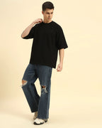 Full body view of the Black Aeternum Men's Oversized T-Shirt styled with denim for a versatile casual aesthetic.