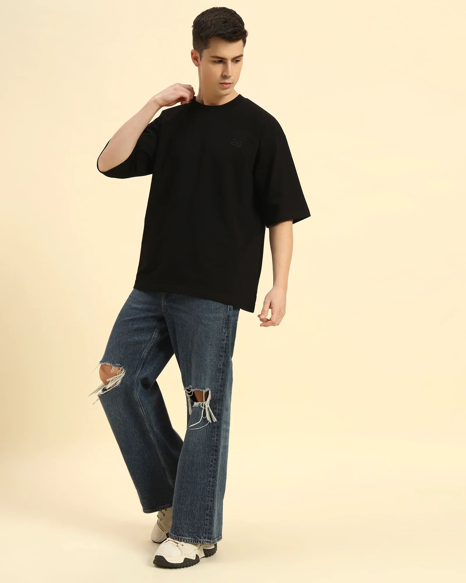 Full body view of the Black Aeternum Men's Oversized T-Shirt styled with denim for a versatile casual aesthetic.