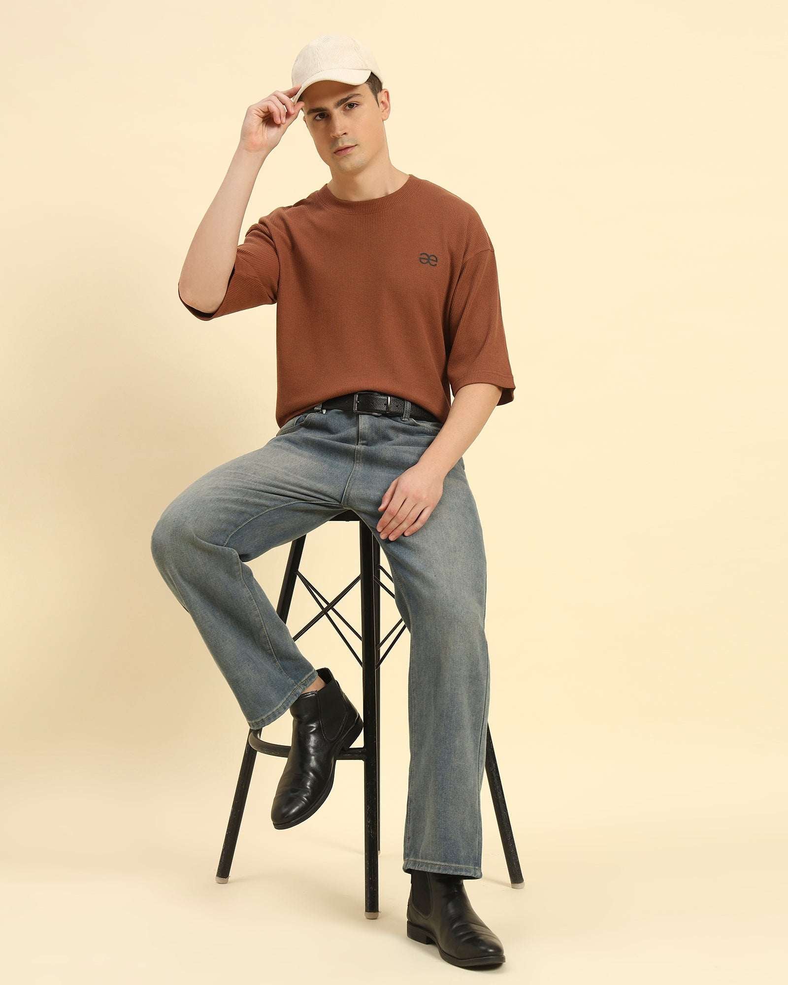 Model seated wearing the Men's Aeternum Oversized Waffle Knit T-Shirt in Coffee Brown, showcasing casual comfort.