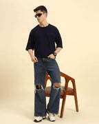Lifestyle view of the Navy Blue Aeternum French Terry Crew Neck styled with denim while seated, showcasing casual comfort.