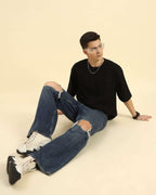 Model seated wearing the Black Aeternum French Terry Crew Neck T-Shirt, styled for a premium streetwear look.