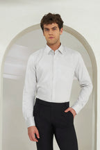 Man wearing a white dress shirt and black pants standing in front of an archway.