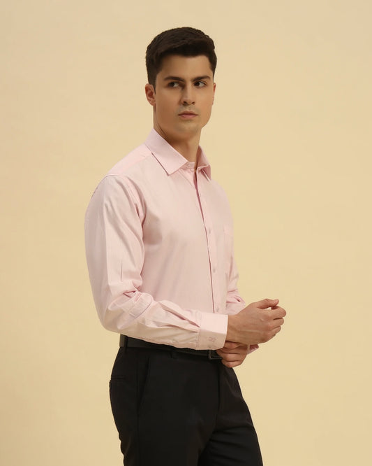 Man wearing a light pink dress shirt against a beige background