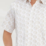 Man wearing a white short-sleeve shirt with a subtle pattern on a plain background